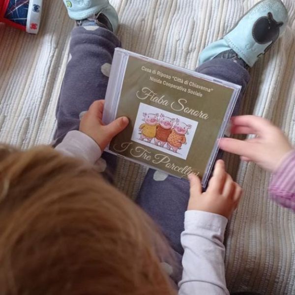 bambino che tiene in mano cd della fiaba sonora dei 3 porcellini